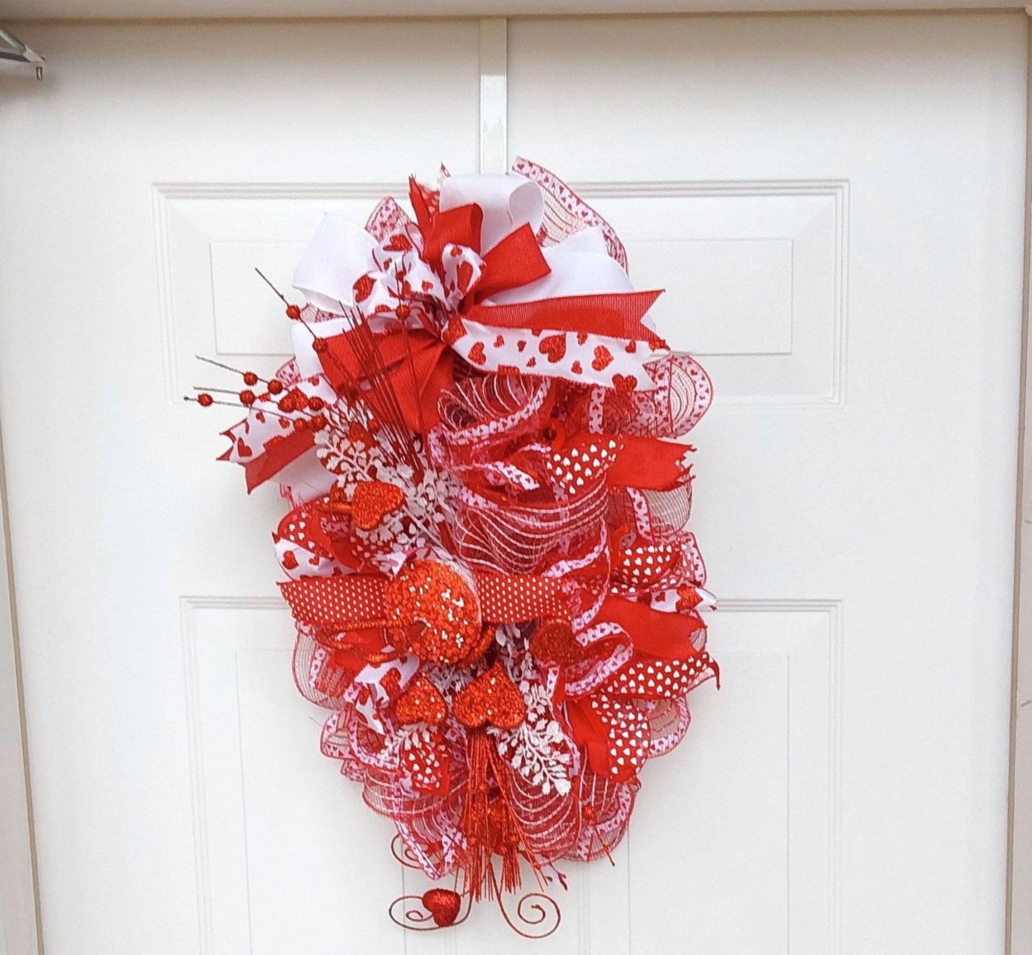 Red white ribboned and mesh wreath with heart embellishments for Valentine's.