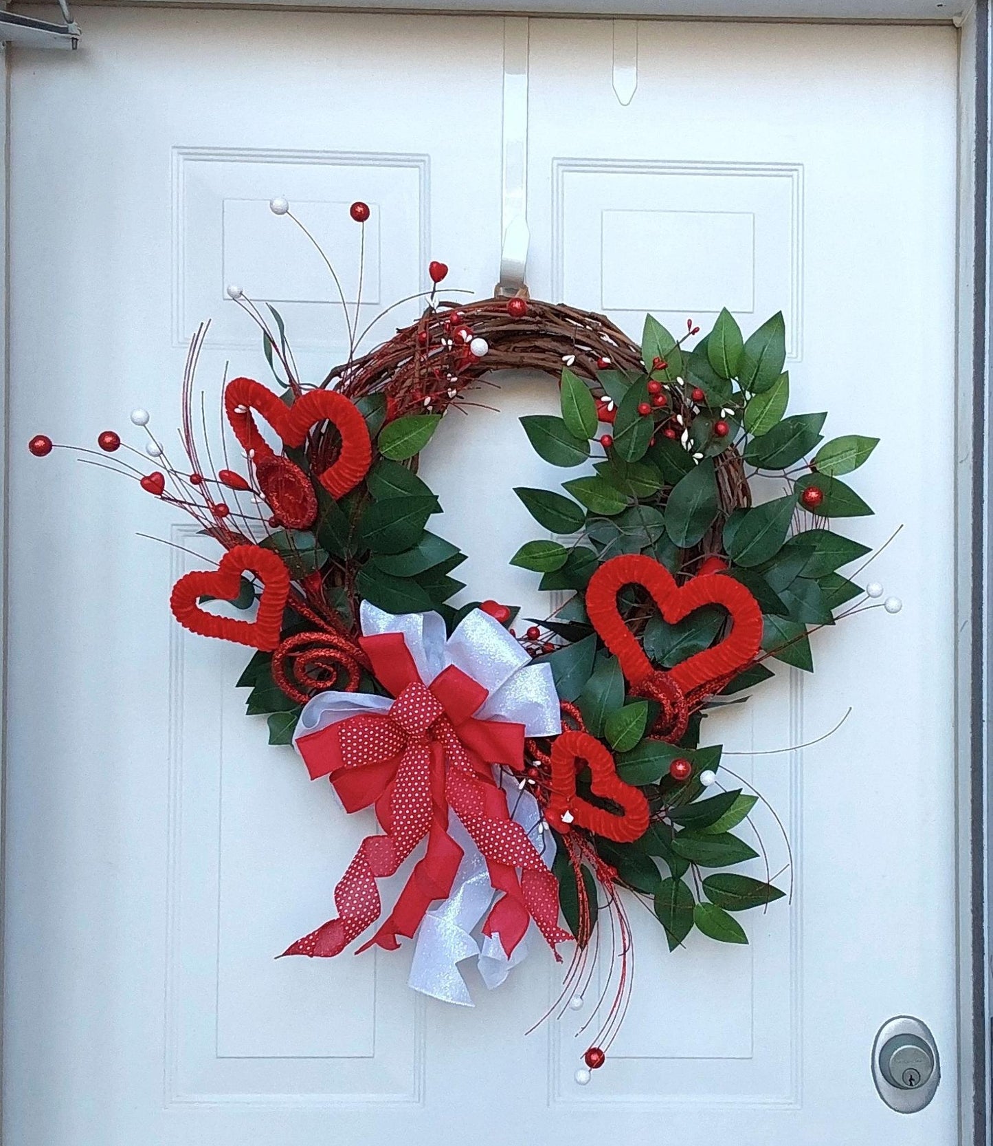 Valentine's wreath with red hearts, swirls, and greenery.