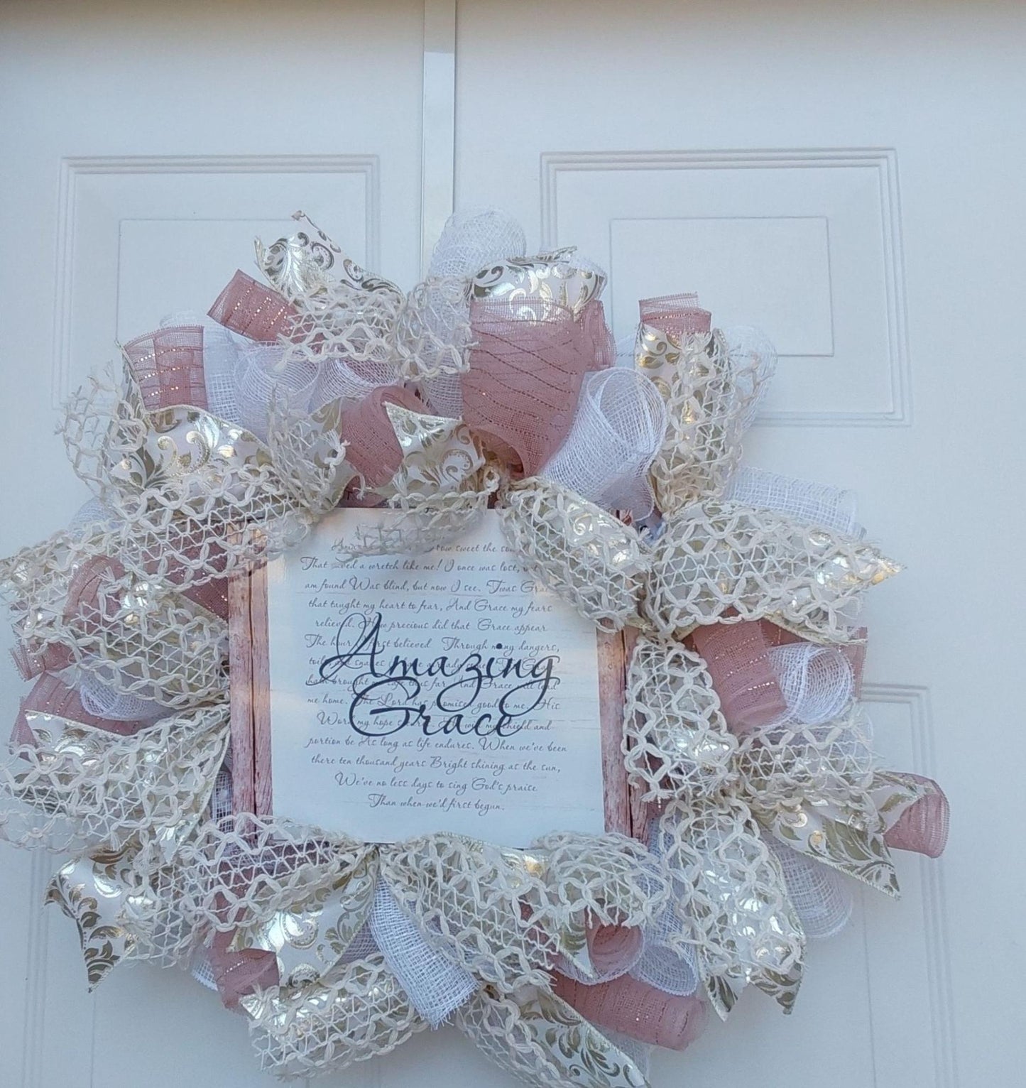 Wreath of gold and pink and white ribbons with an Amazing Grace centerpiece.