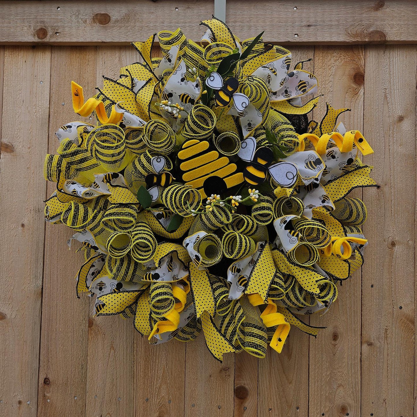 Beehive-inspired wreath with layers of yellow and black mesh and accented with yellow polka dot and bee-theme ribbons