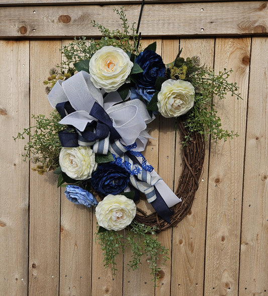 A wreath with blue and white flowers on a fence.