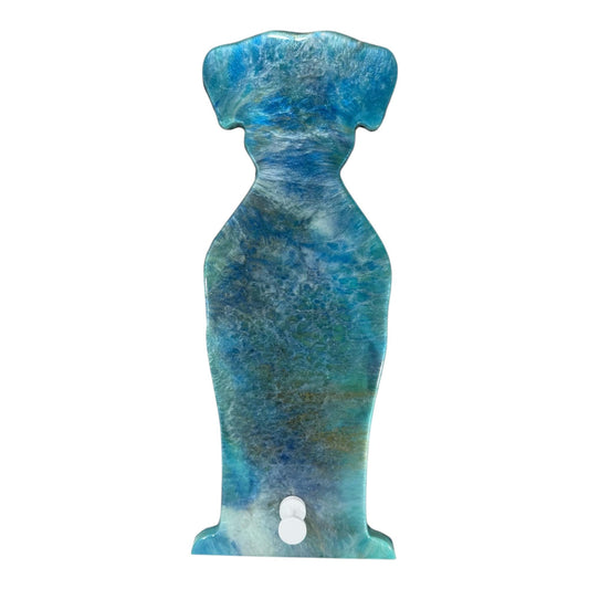 A resin wall art in ocean blue and teal galaxy swirls in the shape of a dog with a silver hook.