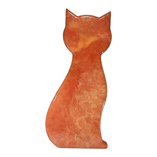 An orange swirled resin wall art in the shape of a cat with a gold hook.