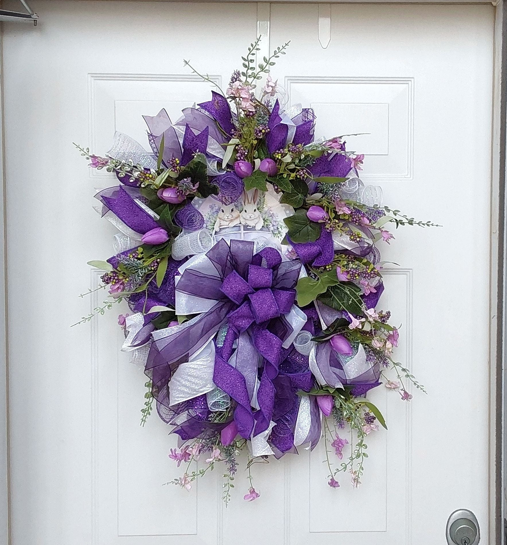 Handcrafted Easter Wreath featuring deep purples with two bunnies on a ride in the centerpiece.