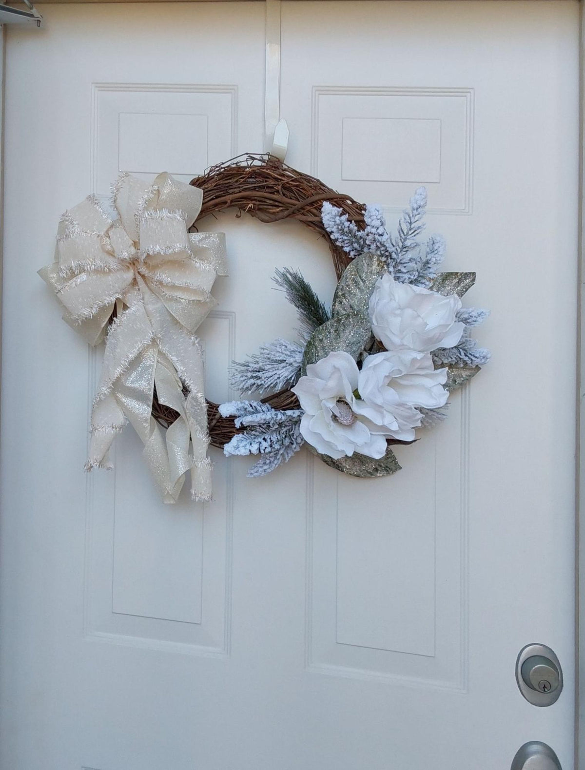 Handcrafted winter wreath with a large bow and magnolias.