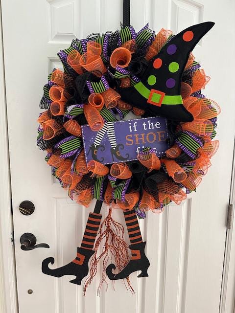 A witch wreath with a sign that reads, "If the shoe fits" at the center.