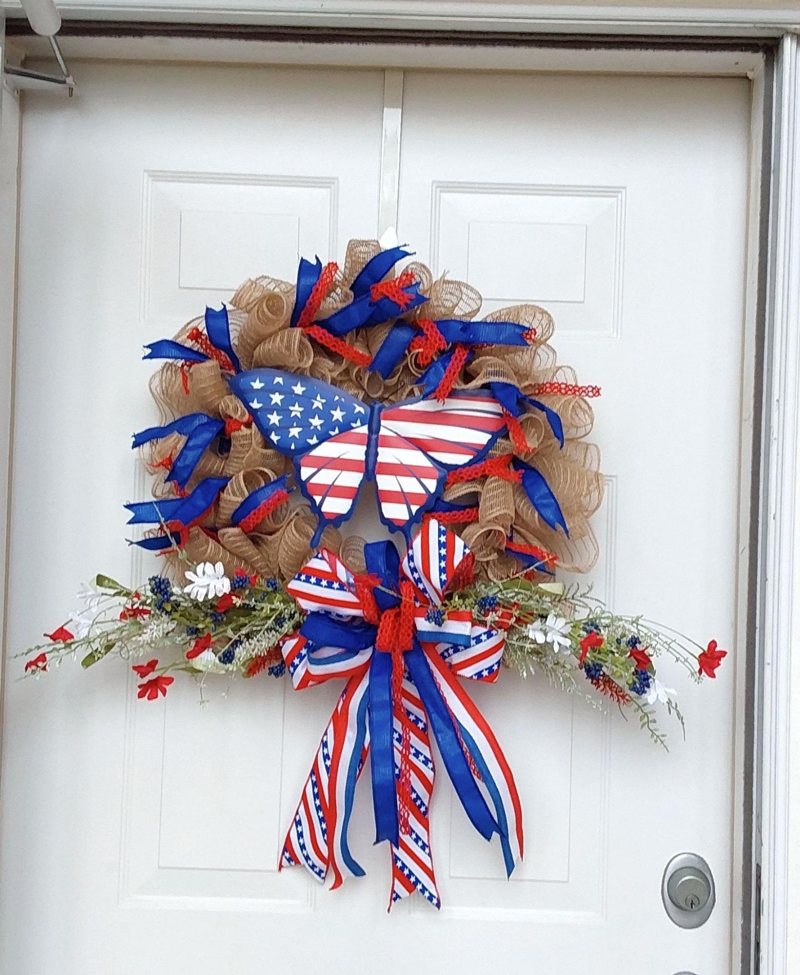 A burlap wreath with red, white, and blue ribbons and a patriotic butterfly centerpiece