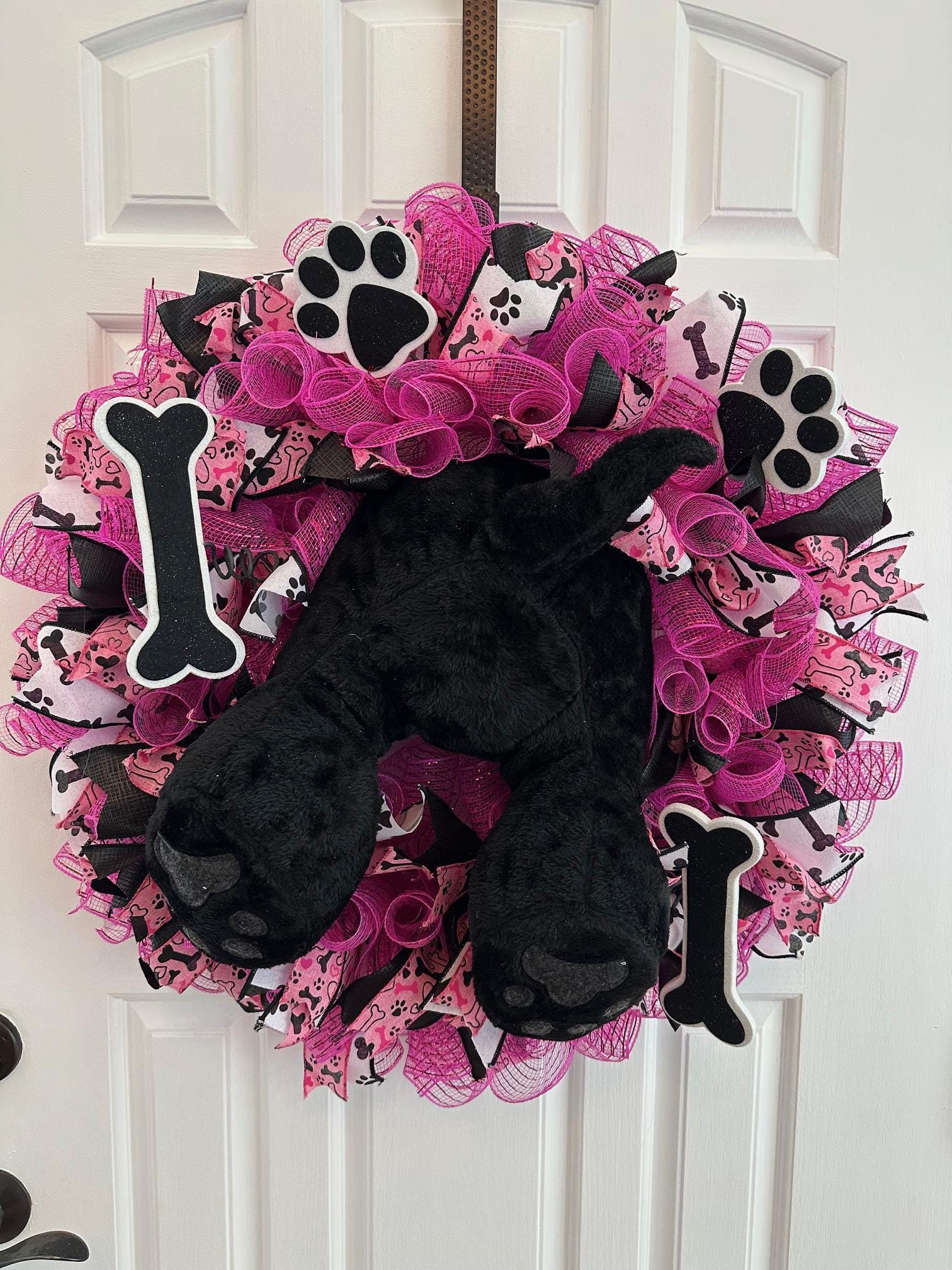 A plush dog butt, paws, and tail surrounded by a pink and black mesh wreath.