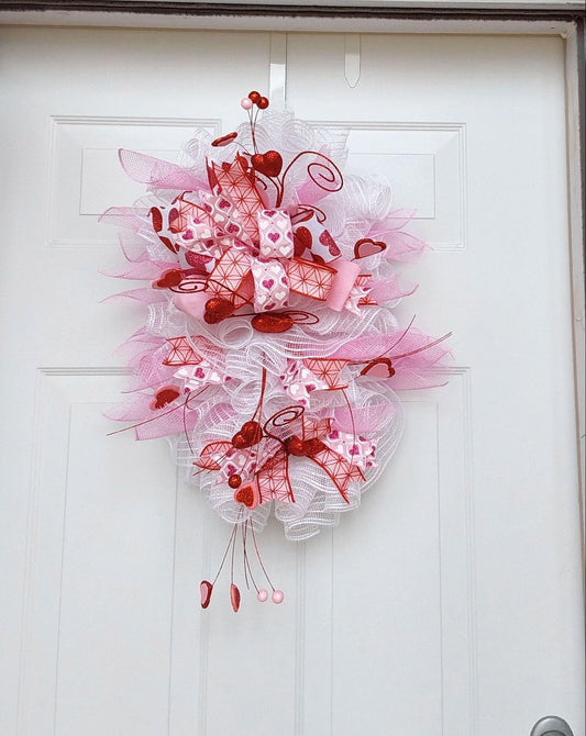 Teardrop wreath with a Valentine's theme in pink, white, and red ribbons and mesh.