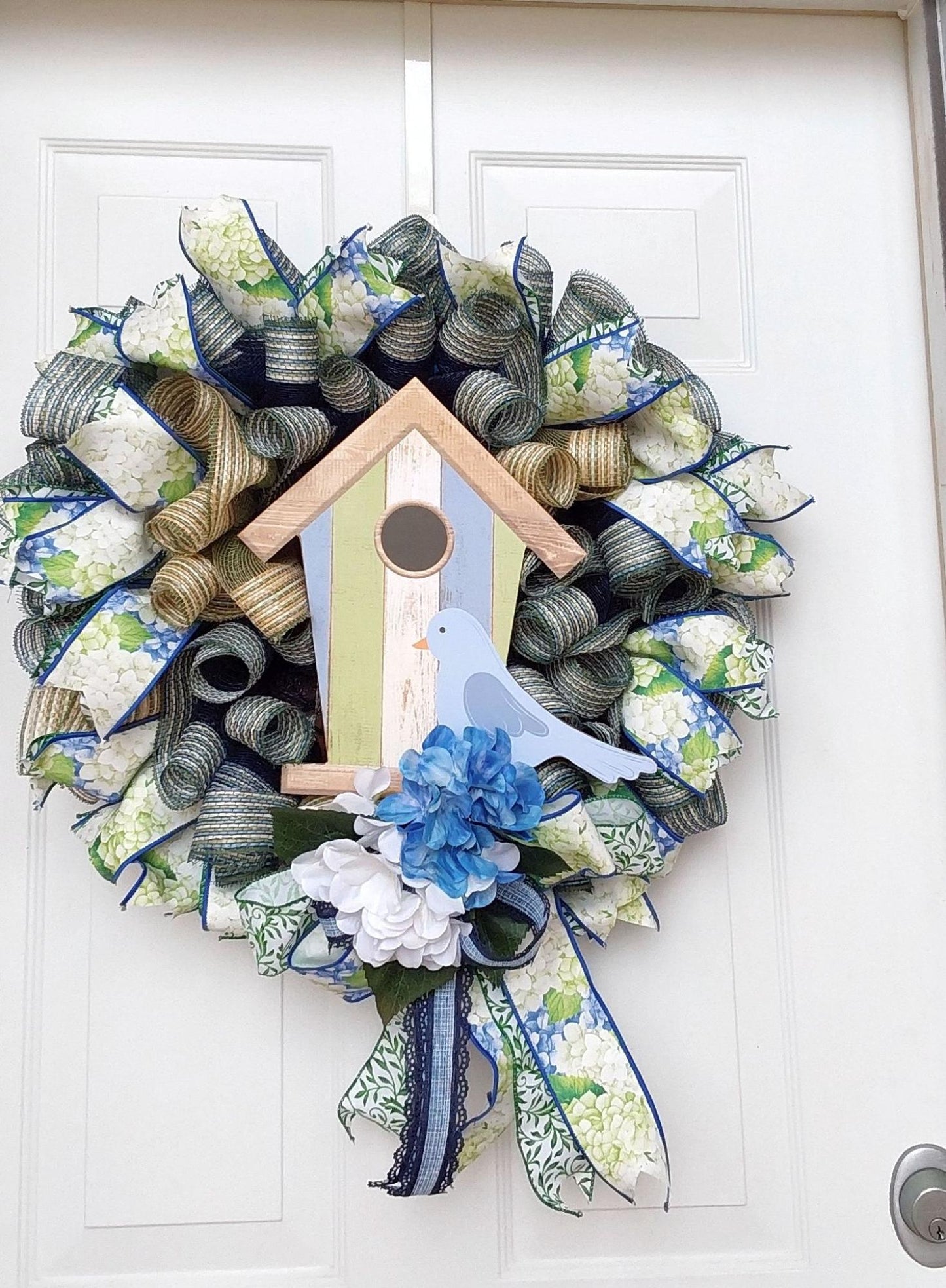 A wreath of ribbons with a birdhouse and blue bird at the center