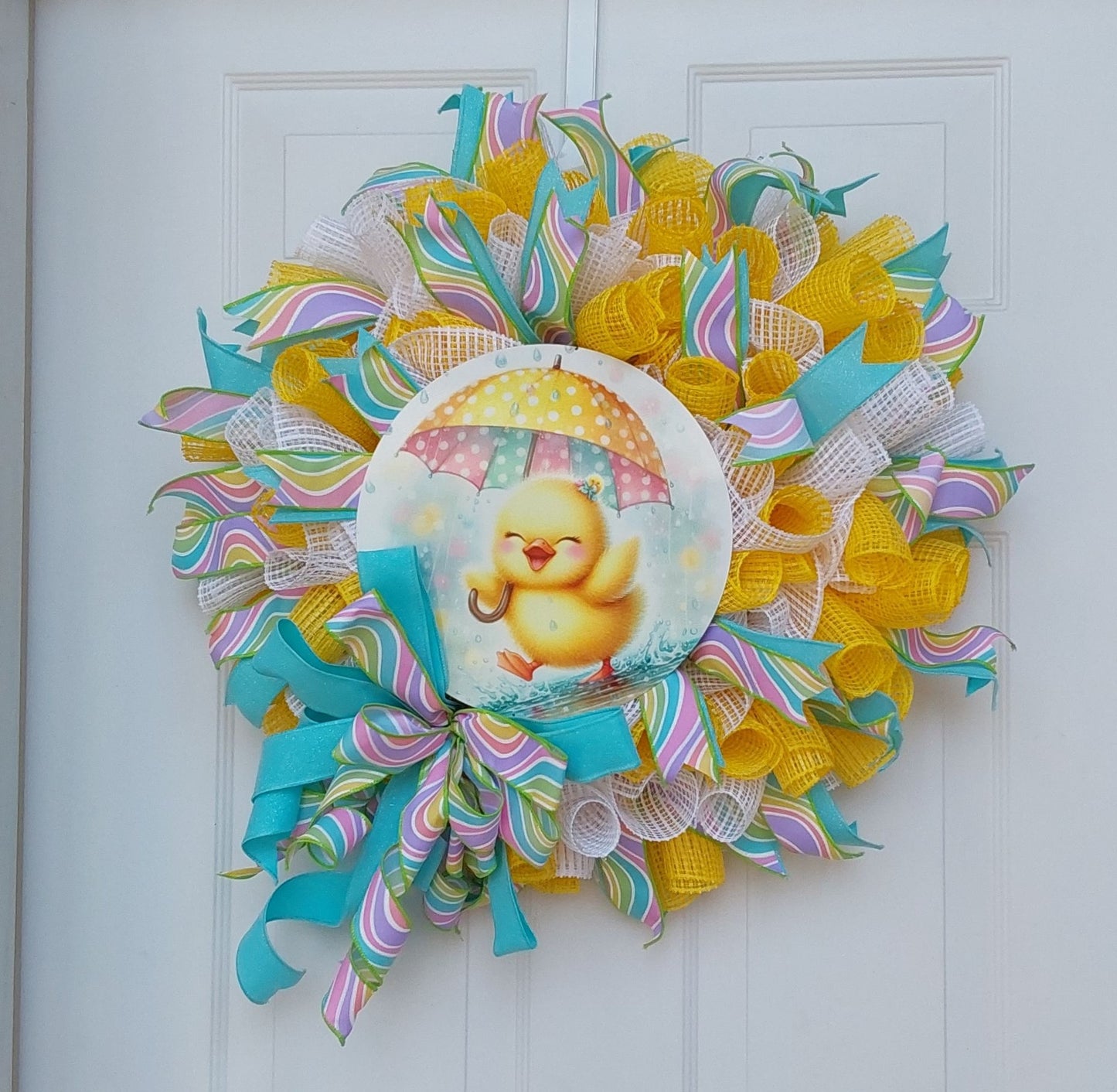 A wreath of spring color ribbons with a chick holding an umbrella at the center.