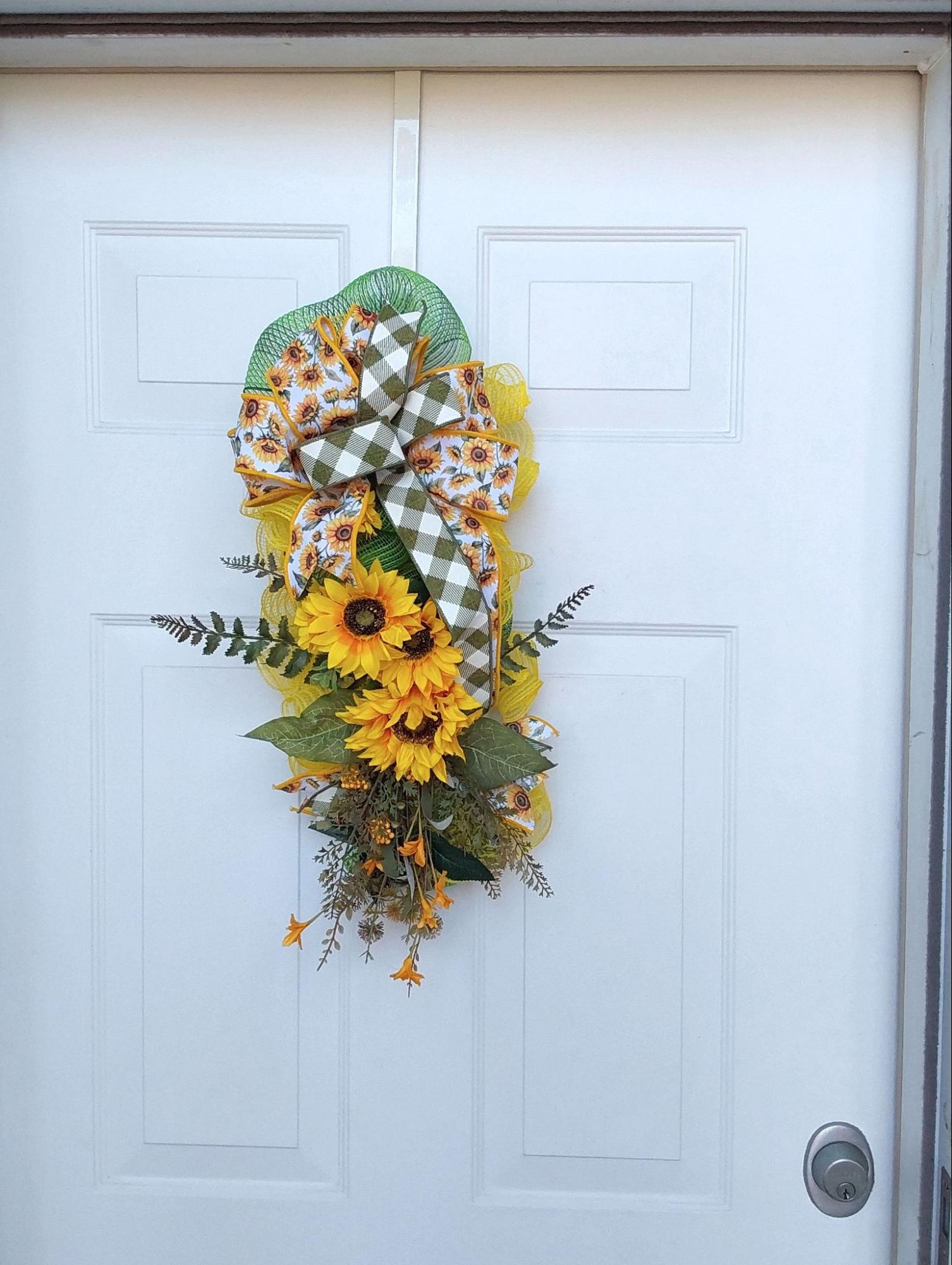 A wreath of ribbon, mesh, and sunflowers with greenery